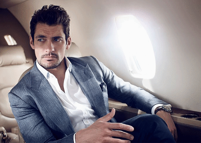 Man in tailored suit relaxes in airplane seat.