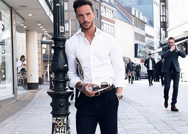 Stylish man in white shirt on city sidewalk.