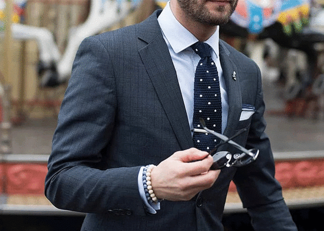 Man in tailored dark gray suit, sunglasses.