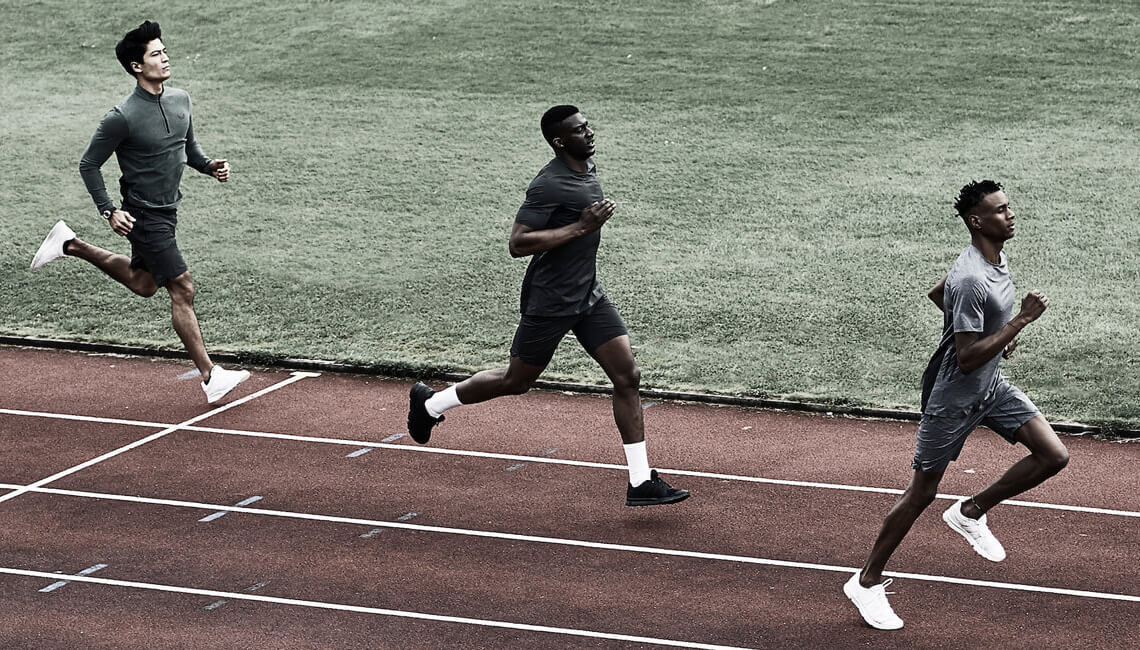 Three men running on track.