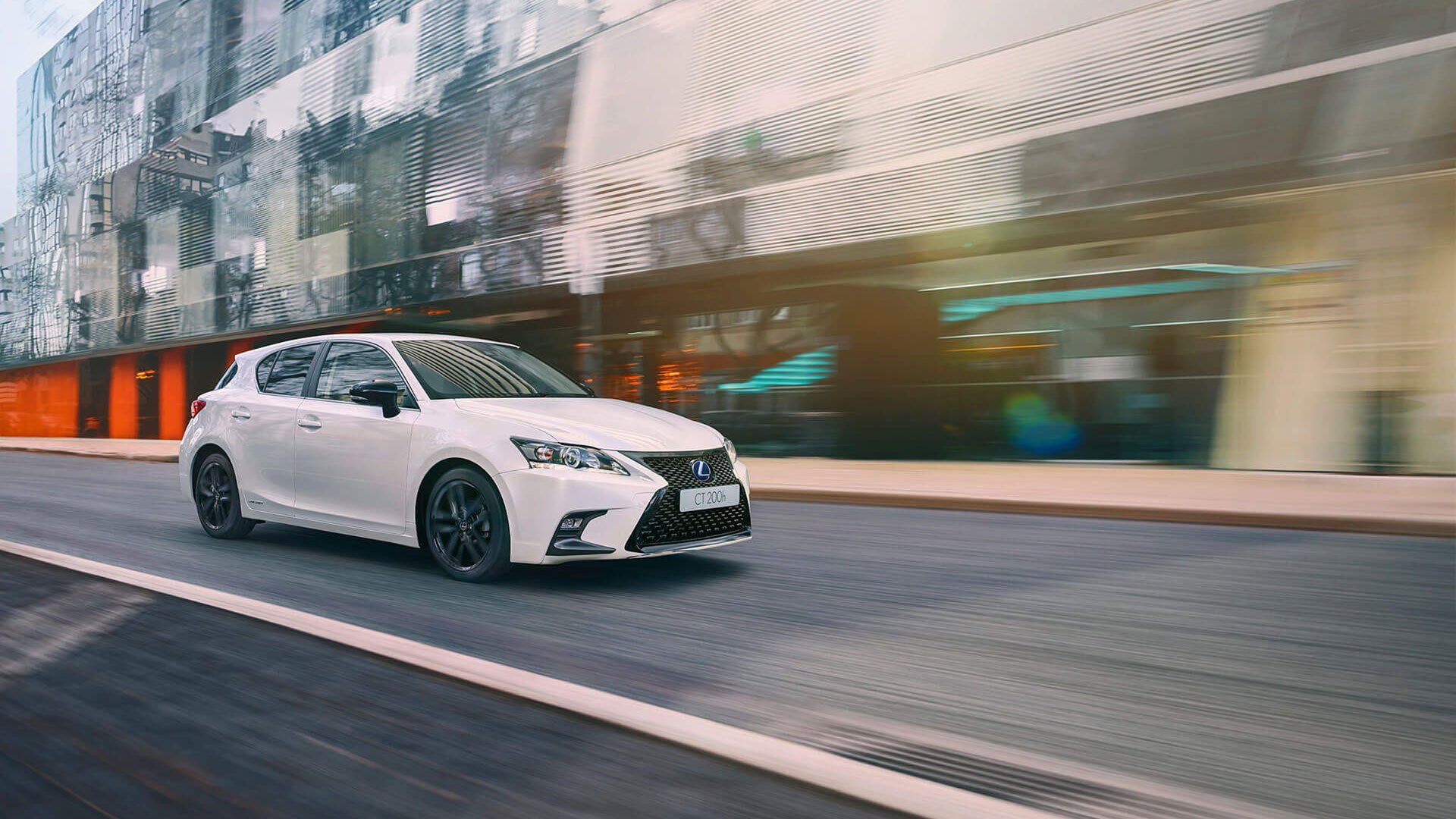 White Lexus hatchback drives city.