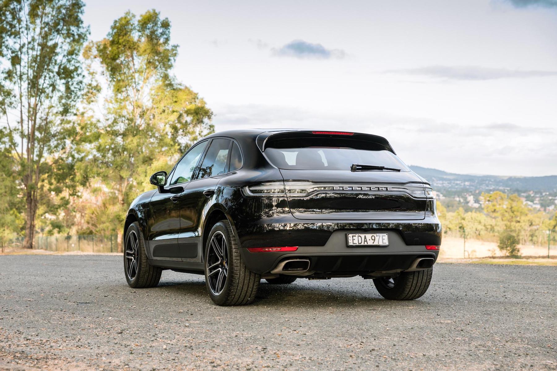 A sleek Porsche Macan parked on gravel.