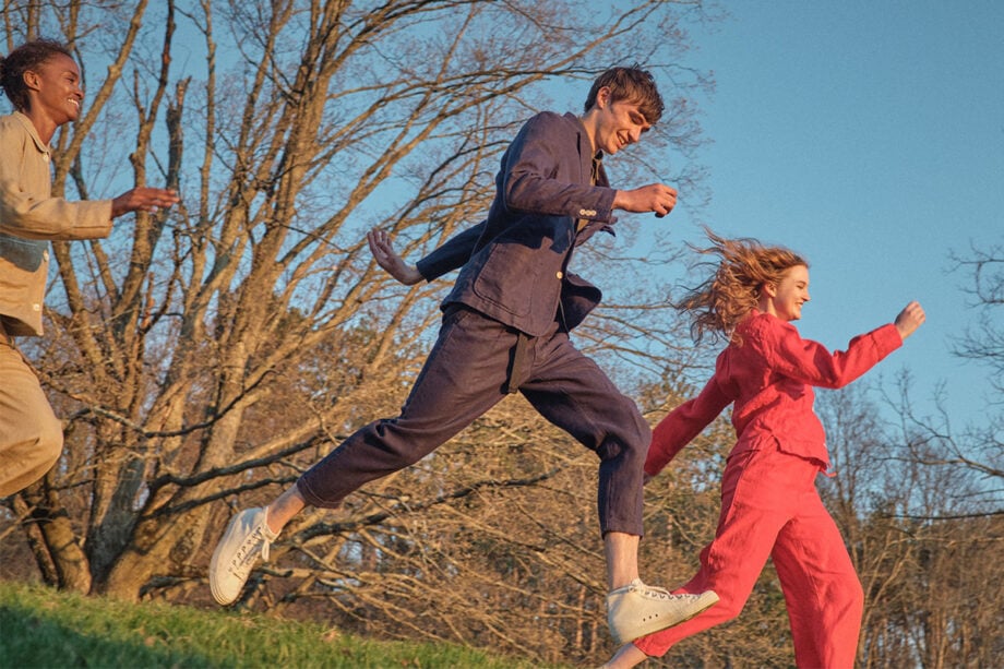 Three people in designer fashion running outdoors.