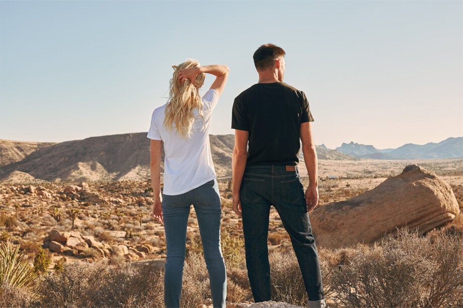 Couple in designer wear overlooks desert landscape.