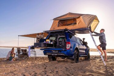 Blue pickup with rooftop tent on Australian beach.