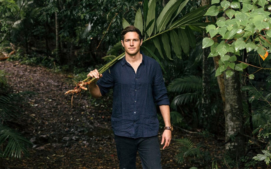 Australian menswear model poses with leafy branch.