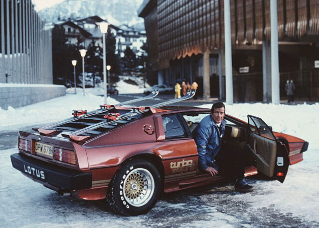 Man exits red Lotus Turbo Esprit on snowy street.