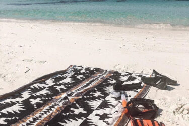 Patterned towel on sand with snorkeling gear.