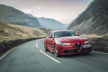 A red sports car cruises mountainous roads.