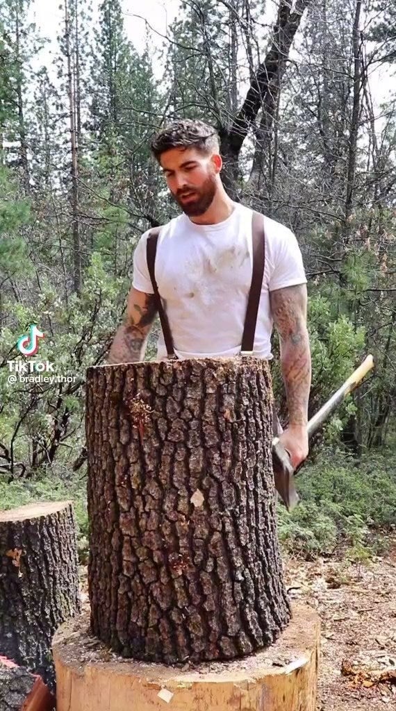 Tattooed man with axe, Bradley Thor, exudes rugged charm.