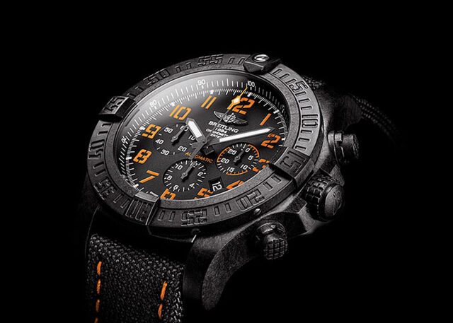 Close-up of black and orange Breitling watch.