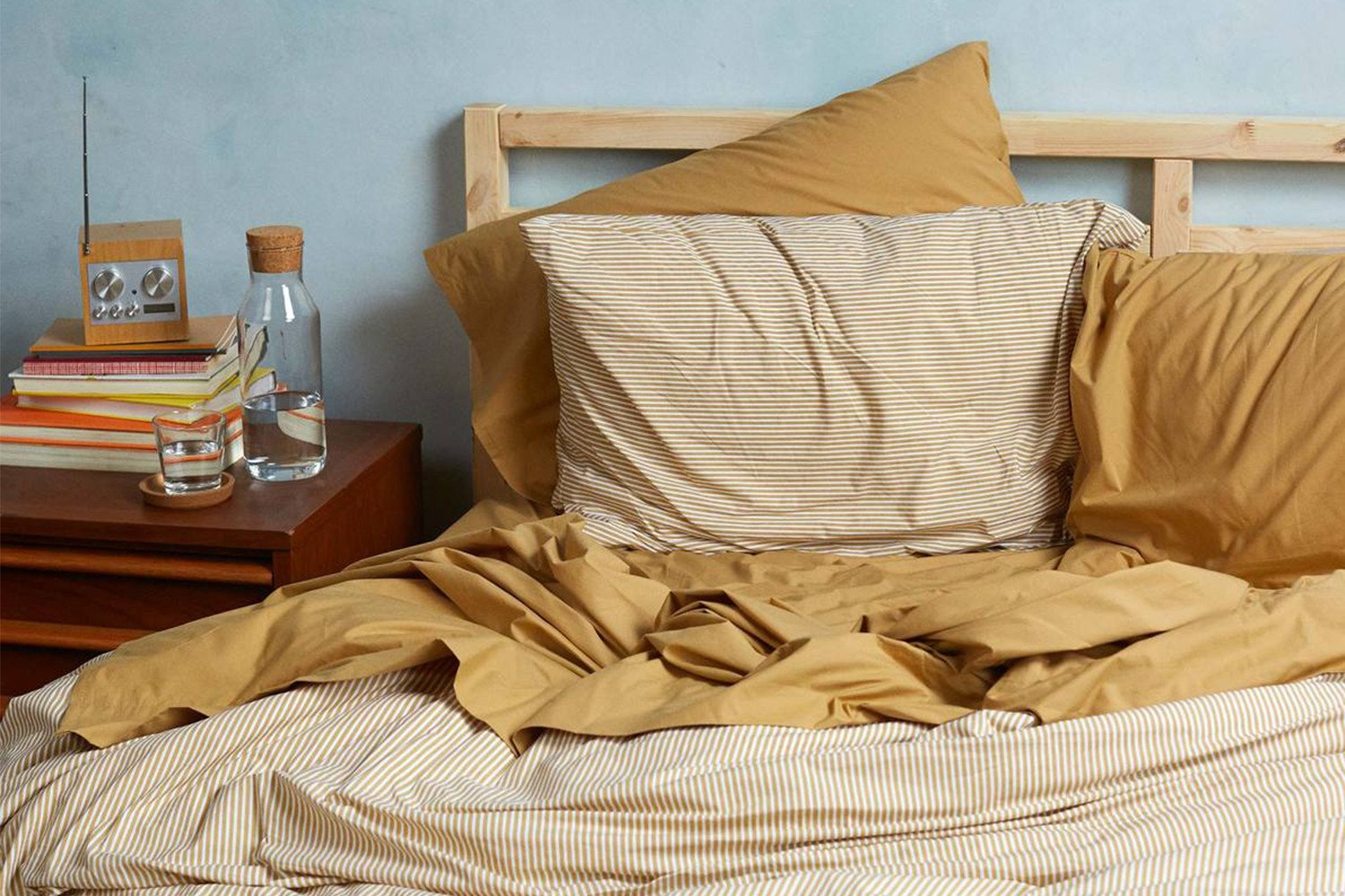 Bed with striped linen, nightstand.