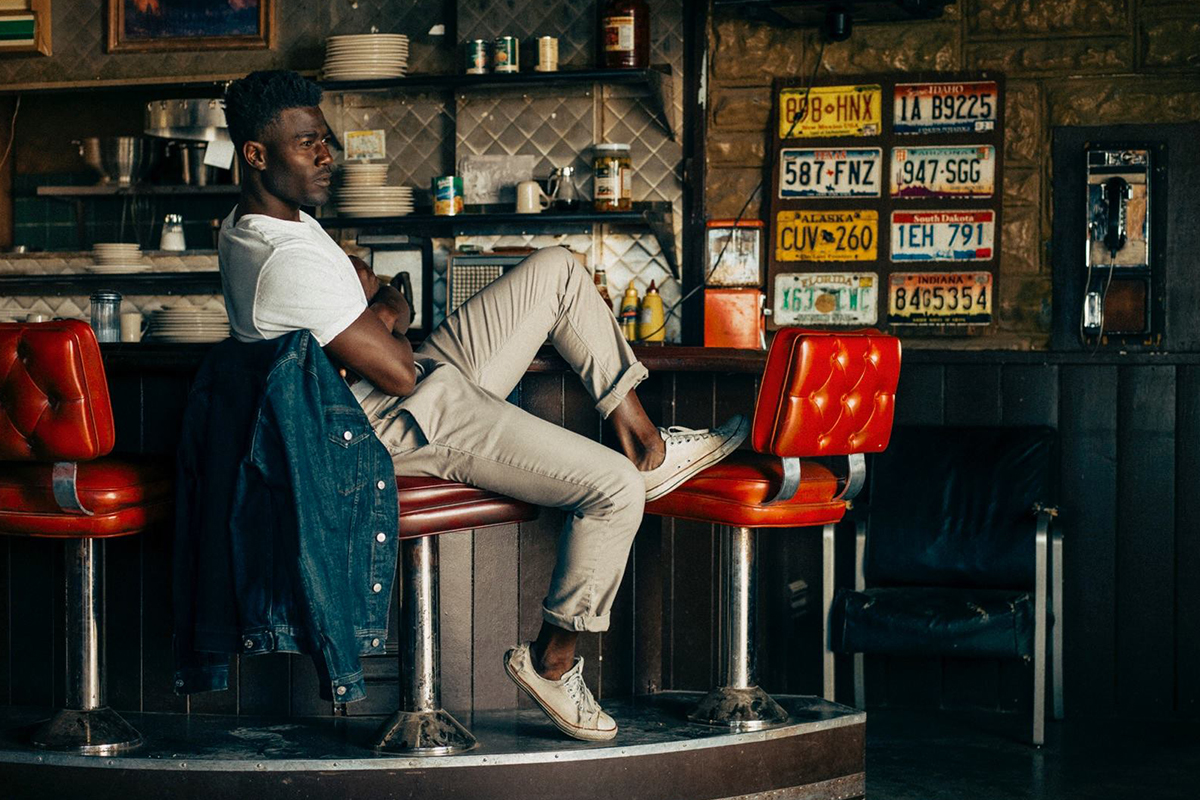 Man relaxes in diner with denim jacket.