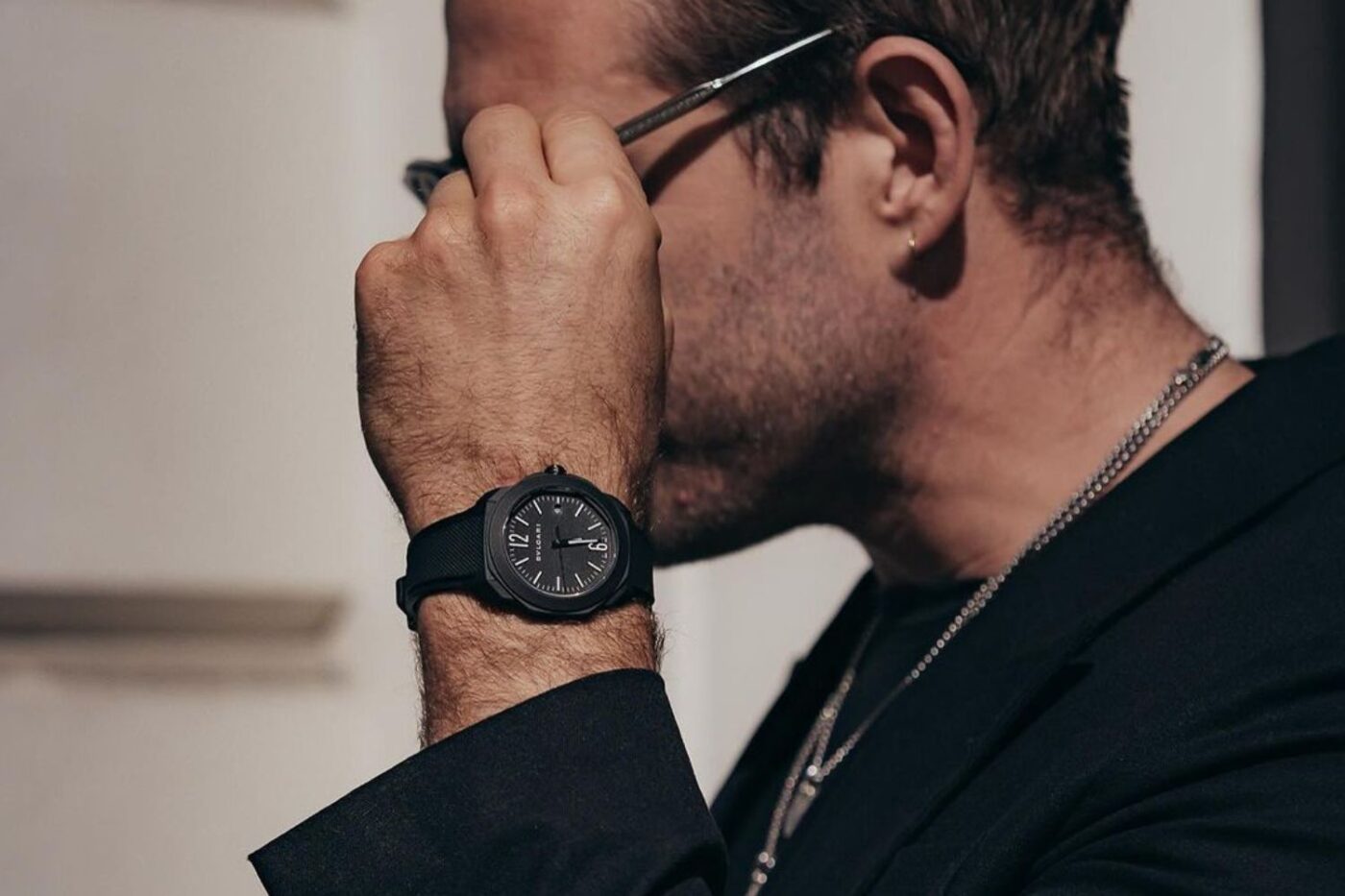 Wearing suit, showcasing luxury watch.