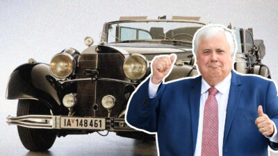 Man in blue suit poses with vintage Mercedes.