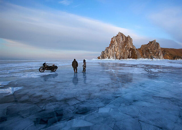 Two people beside a motorcycle on Russian ice.