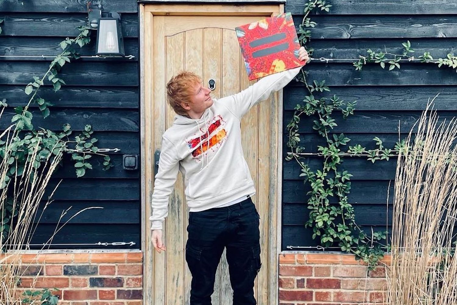 Red-haired person poses with Ed Sheeran-like album hint.