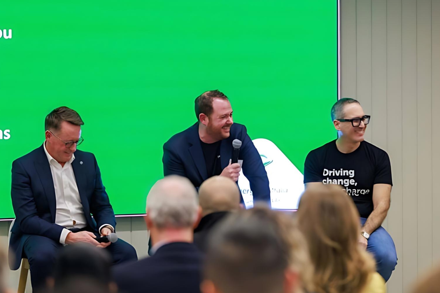 Three men discuss used EV prices onstage.