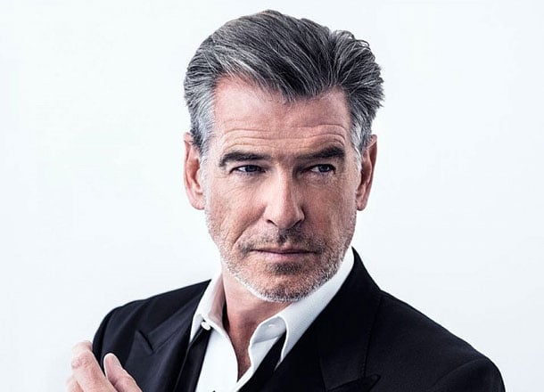 Distinguished grey-haired man in suit, serious look, light background.