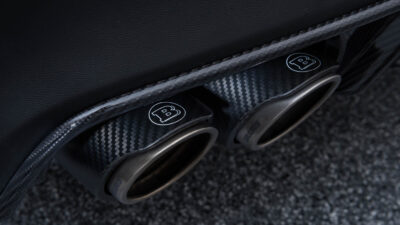 Close-up of performance car's carbon fiber exhaust with "B" logo.