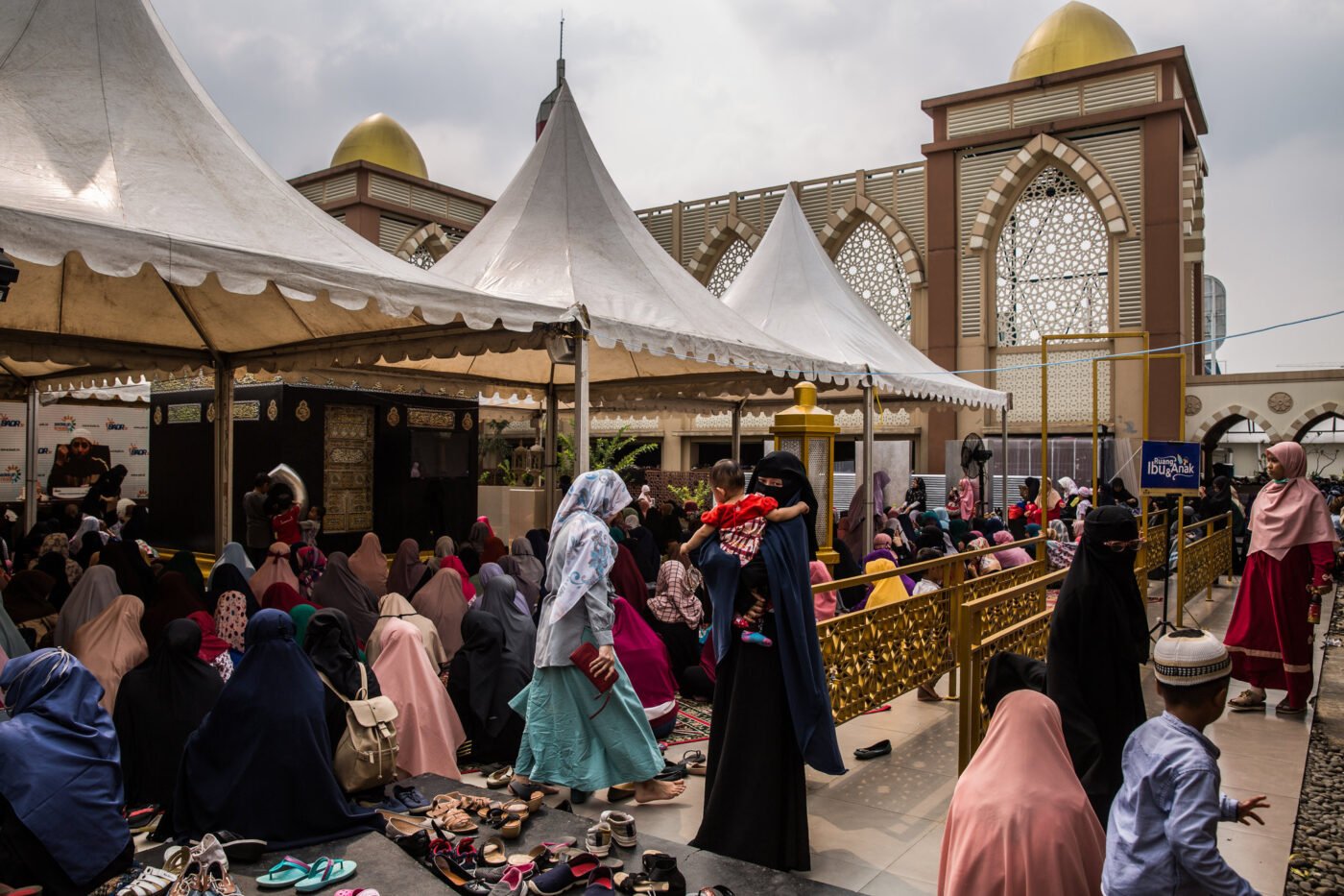 Women in colorful hijabs gather near Indonesian mosque.