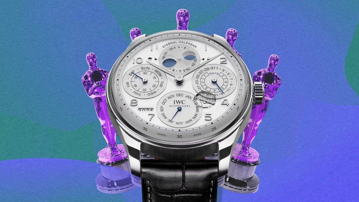 A silver IWC watch beside purple statuettes.