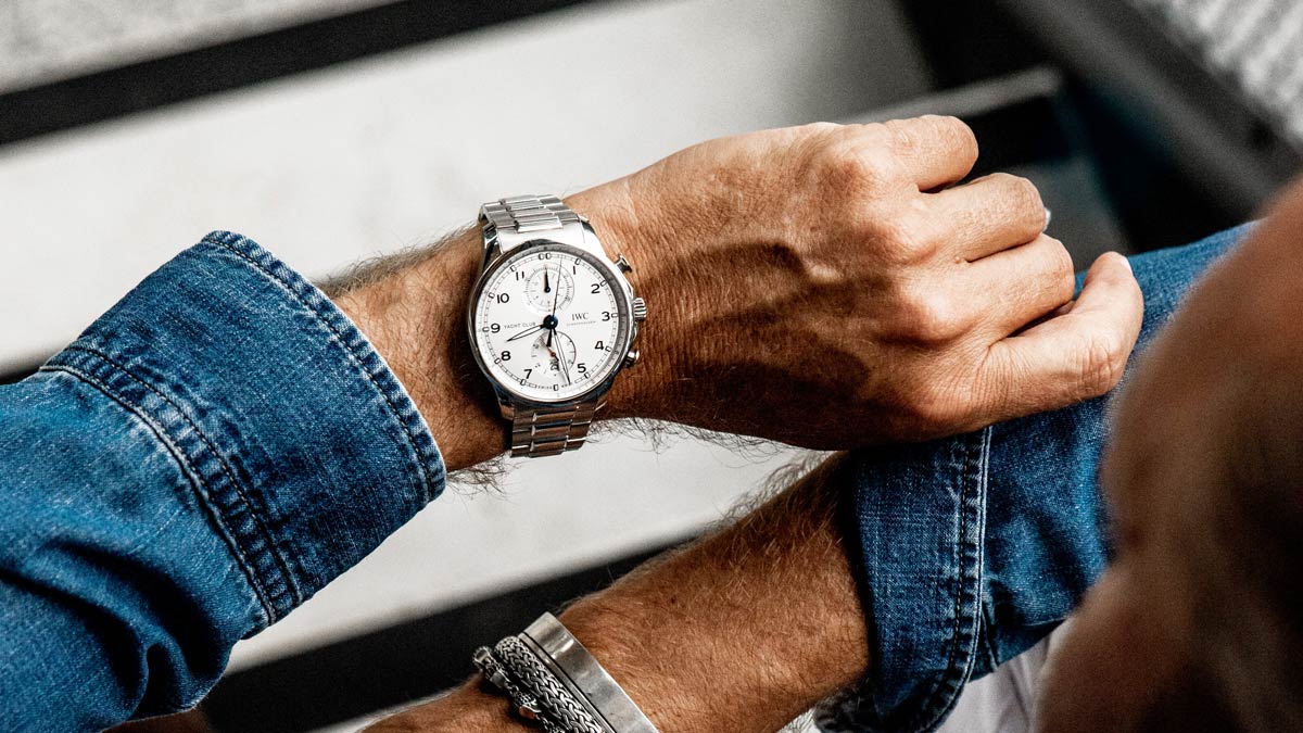 A person wears an IWC watch and bracelets.