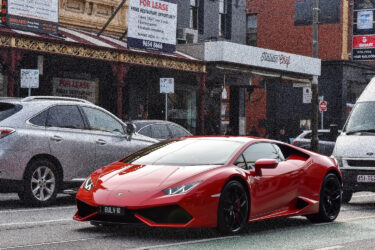 Red sports car on city street, Australia.