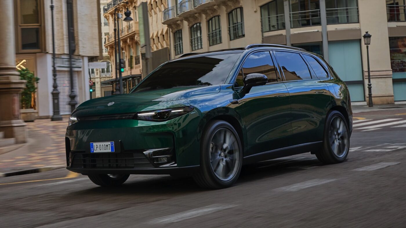 A green SUV cruises through a quiet city.