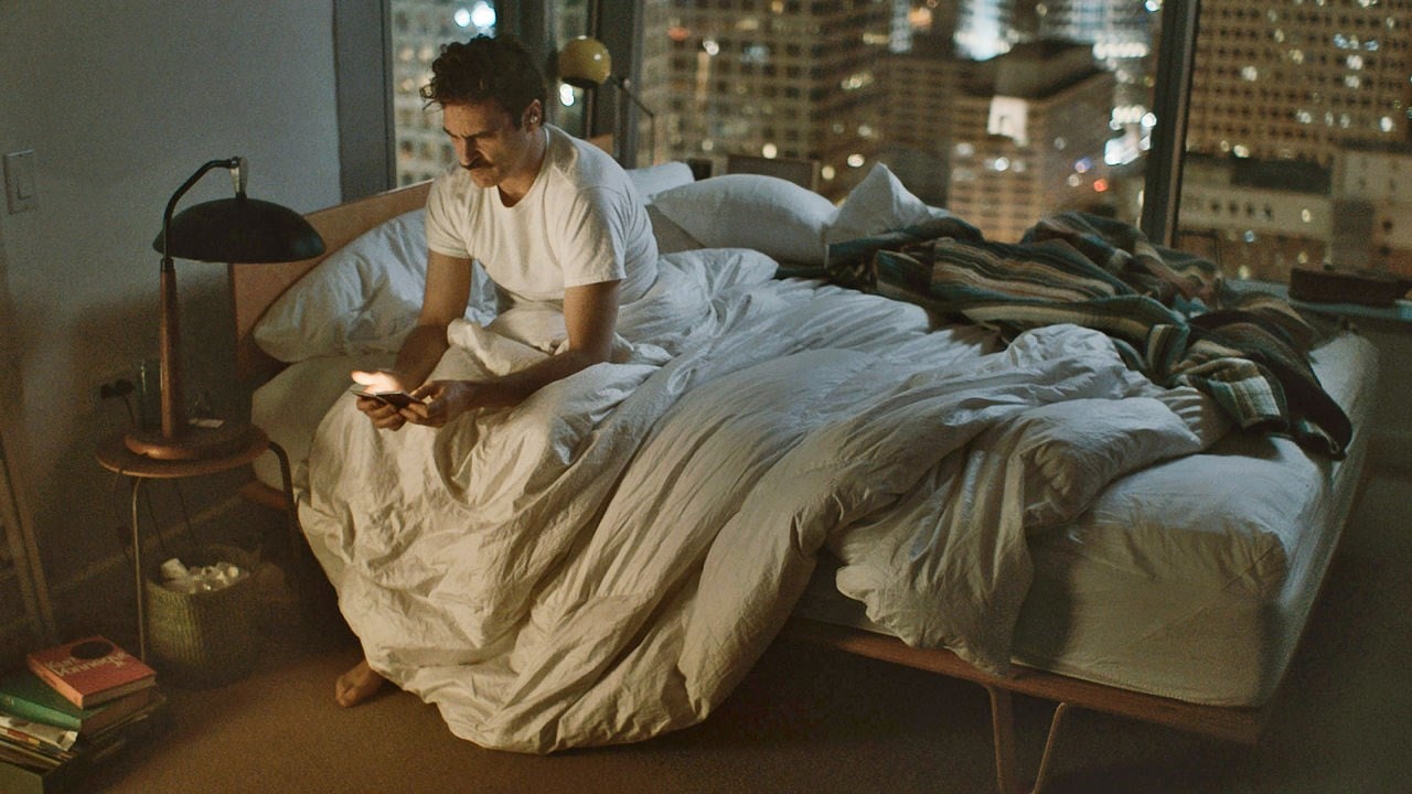 Still from 'Her' (2013) of man sitting on bed, looking lost