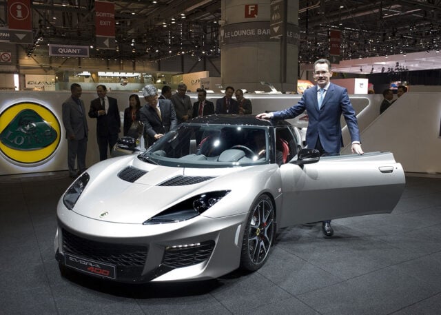 Man poses with Lotus Evora 400 at auto show.