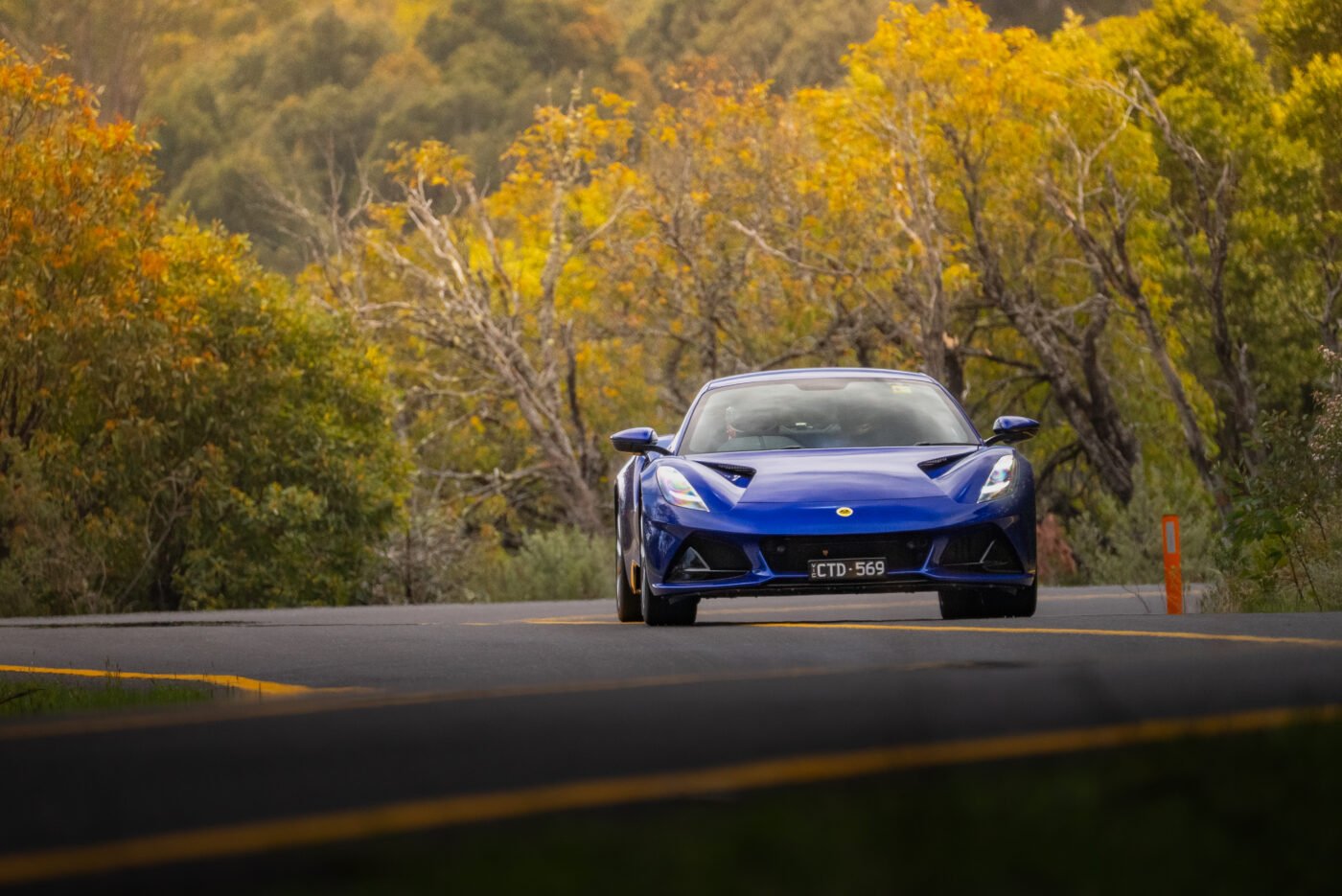 A blue Lotus sports car on autumn road.