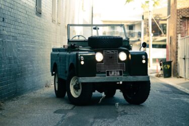 Vintage green Land Rover in narrow alley.