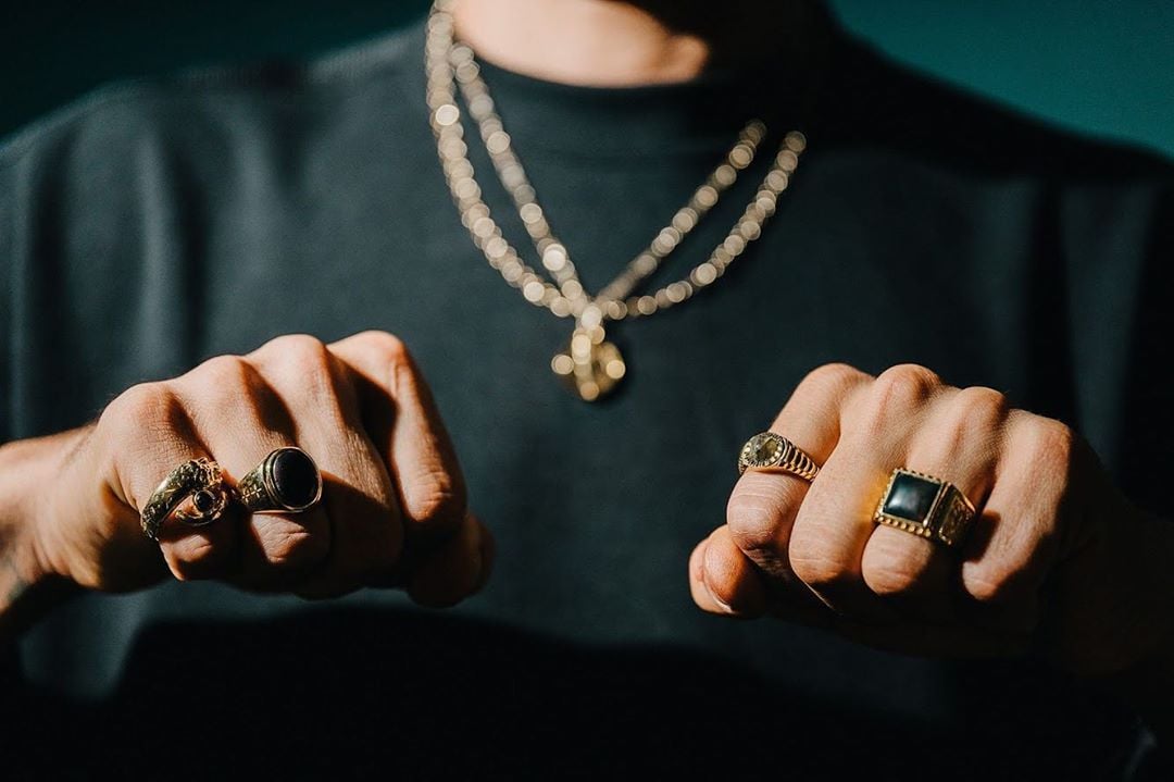 Flaunting stylish rings, gold chains.