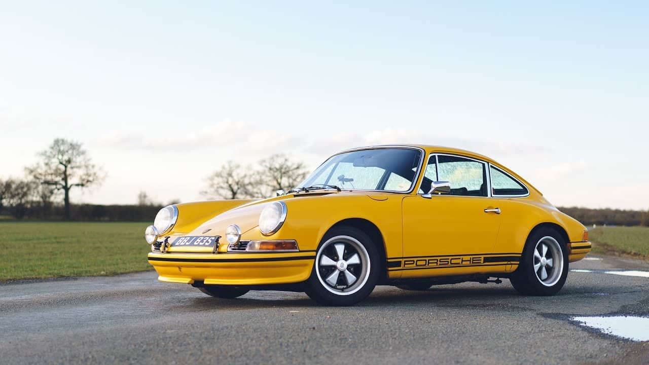 Yellow Porsche vintage car with black stripe.