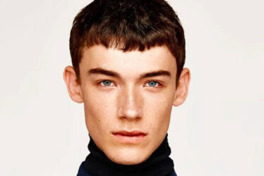 Young man in turtleneck, French crop haircut.