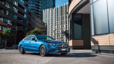 Blue Mercedes-Benz sedan parked on city street.