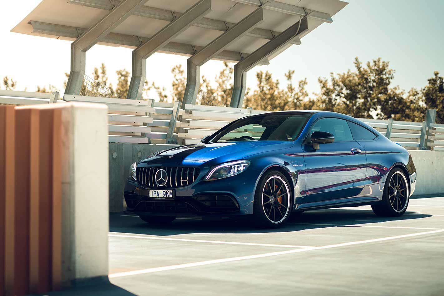 Blue Mercedes-Benz coupe parked under partial roof.