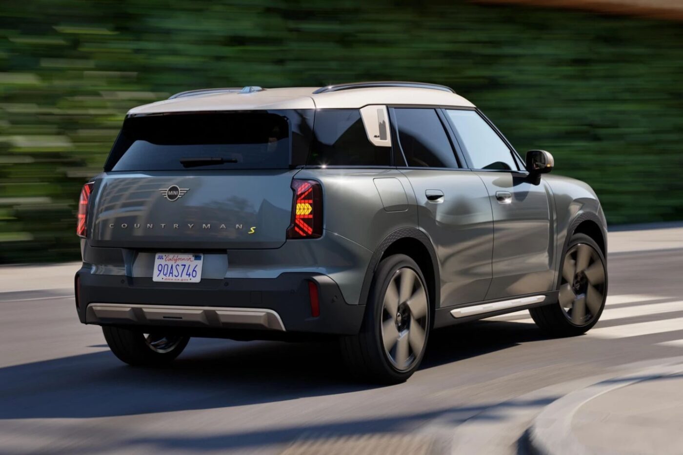 A gray MINI Countryman S drives amid greenery.