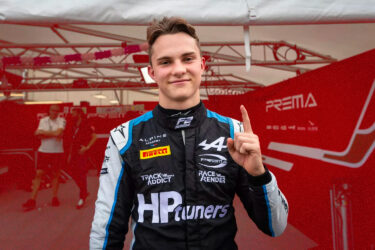 Young racer celebrates F1 sponsorship, smiling.