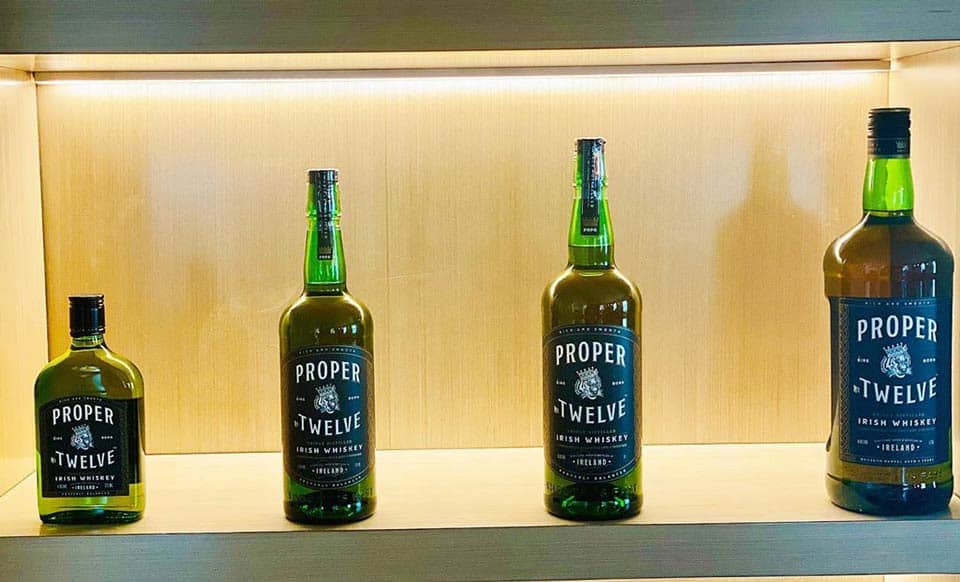 Proper Twelve Irish Whisky bottles on wooden shelf.