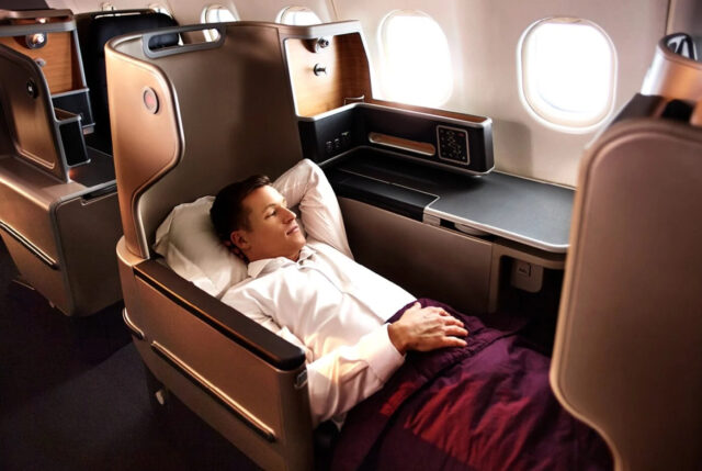 Person enjoys Qantas comfort in airplane cabin.