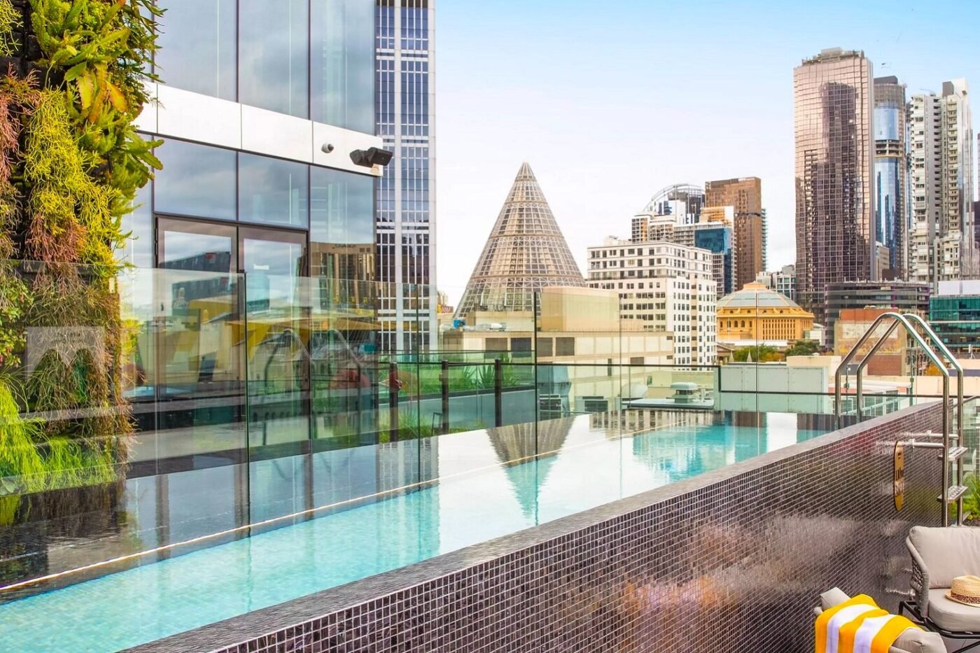 Rooftop infinity pool overlooks city skyline, pyramid nearby.