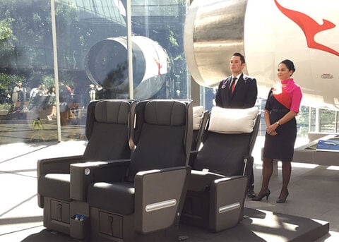 Airline staff showcase Premium Economy in showroom.