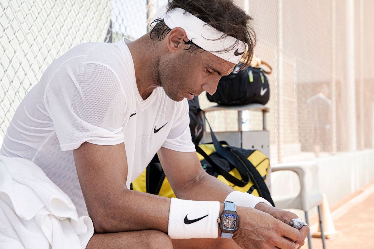 Tennis player checks phone, French Open backdrop.