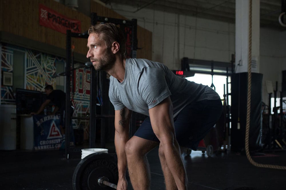 Man lifting barbell in gym.