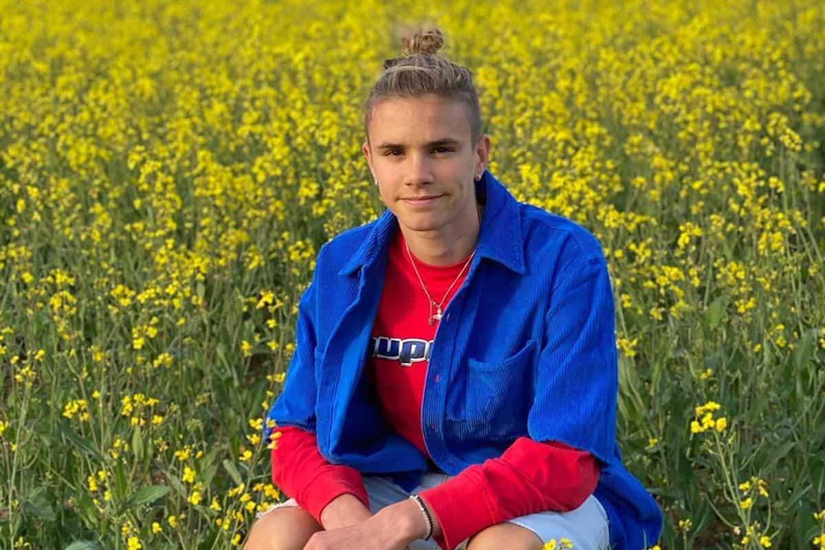 Hair-up person enjoys floral field.