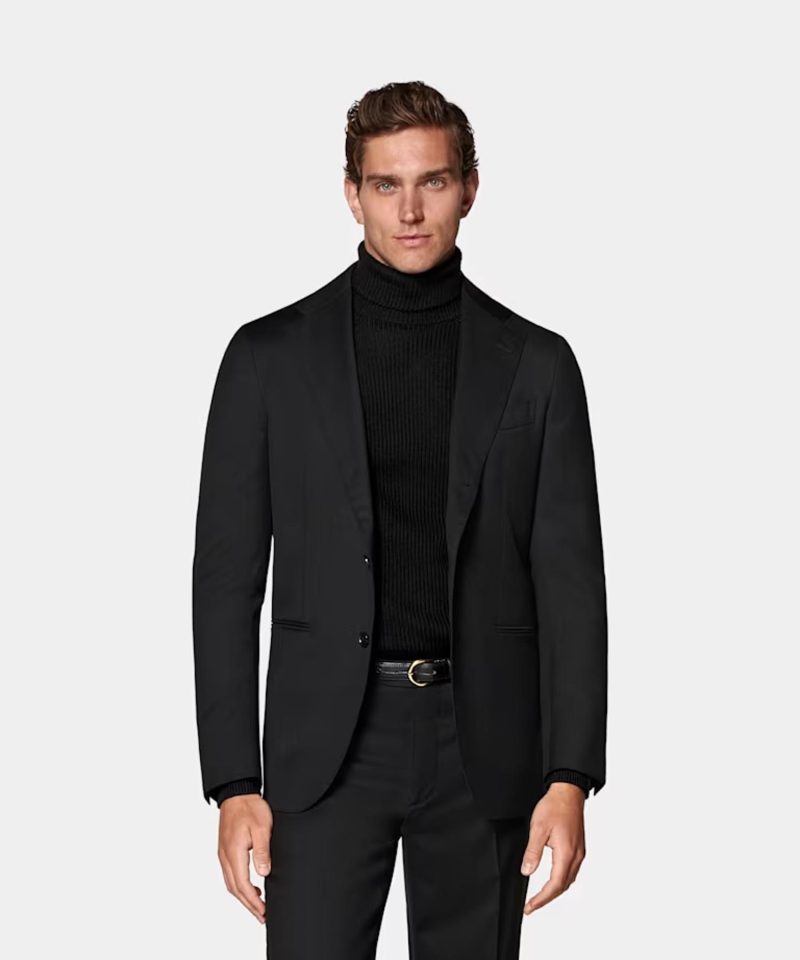 A man wearing black turtle neck with black blazer