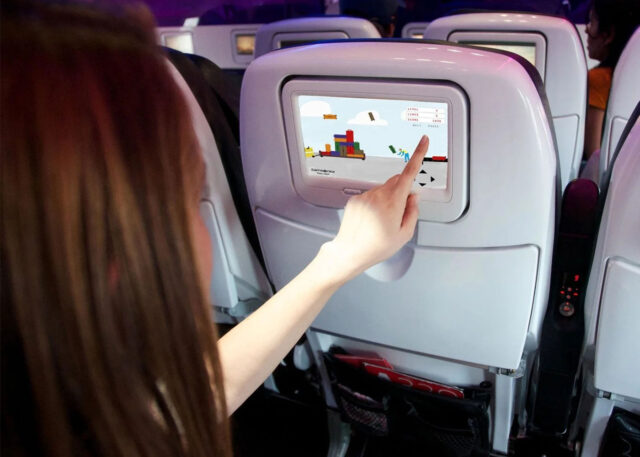 Person plays video game on airplane touchscreen.