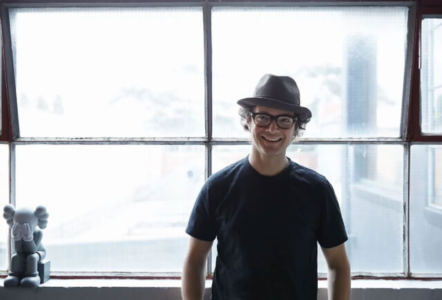 Person in glasses and sneakers by window.